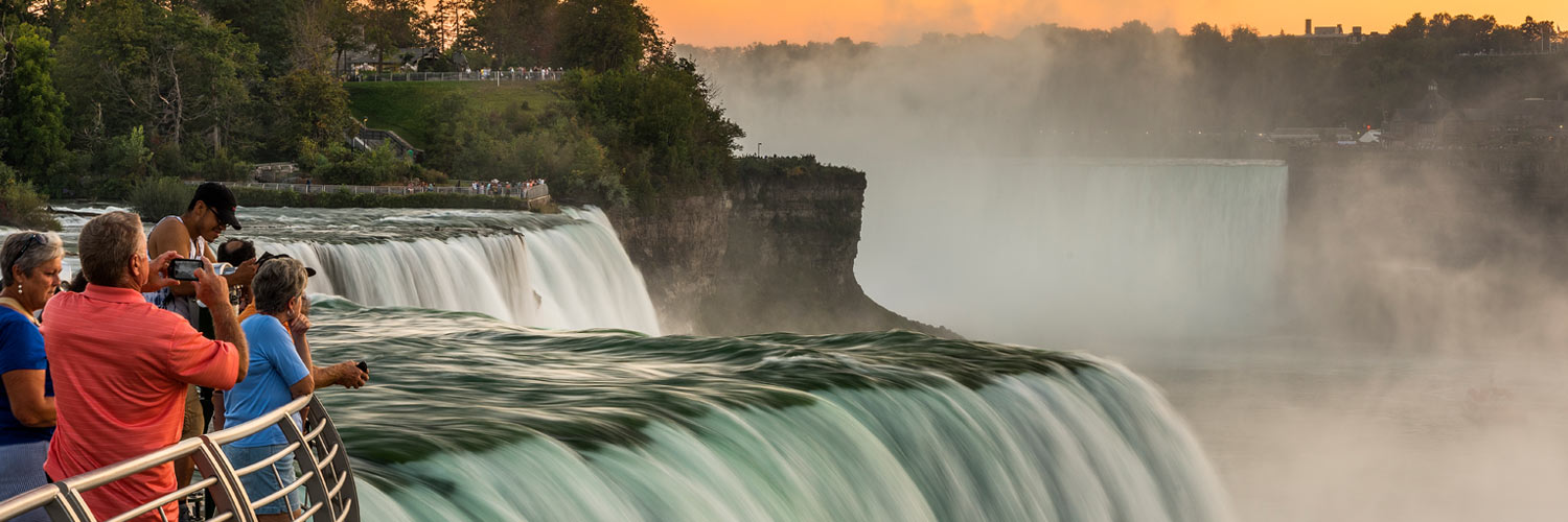 Tourists admire Niagara Falls at sunset at Niagara Falls State Park
