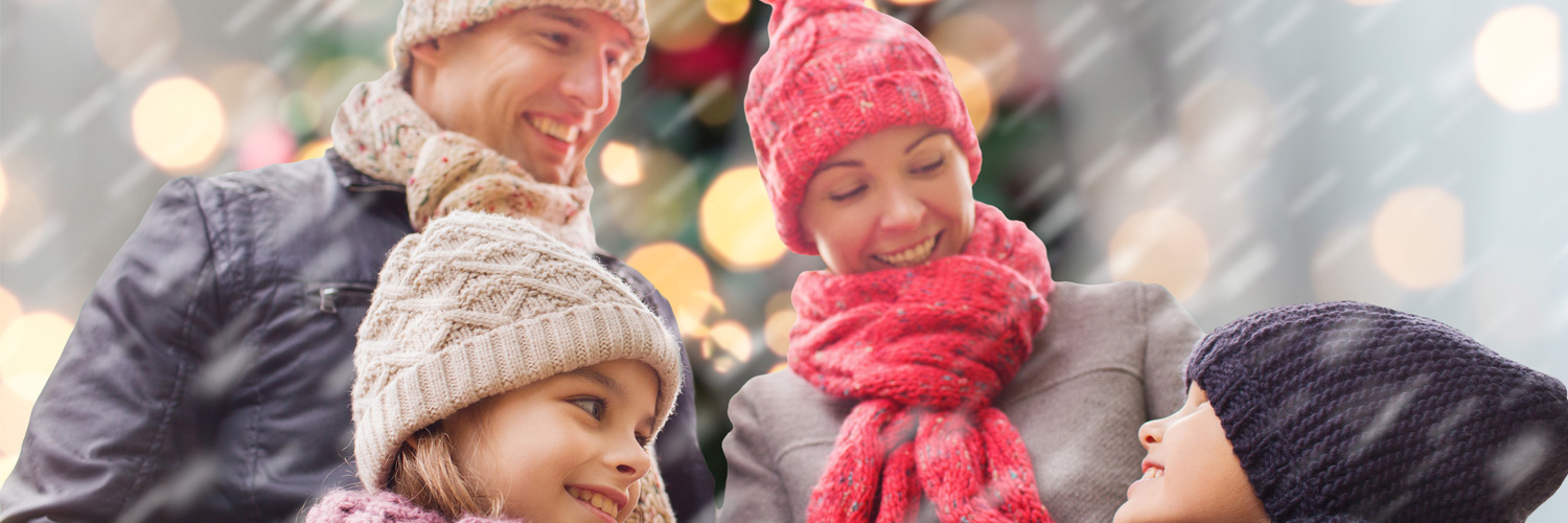 happy family in winter clothing with holiday lights in the background
